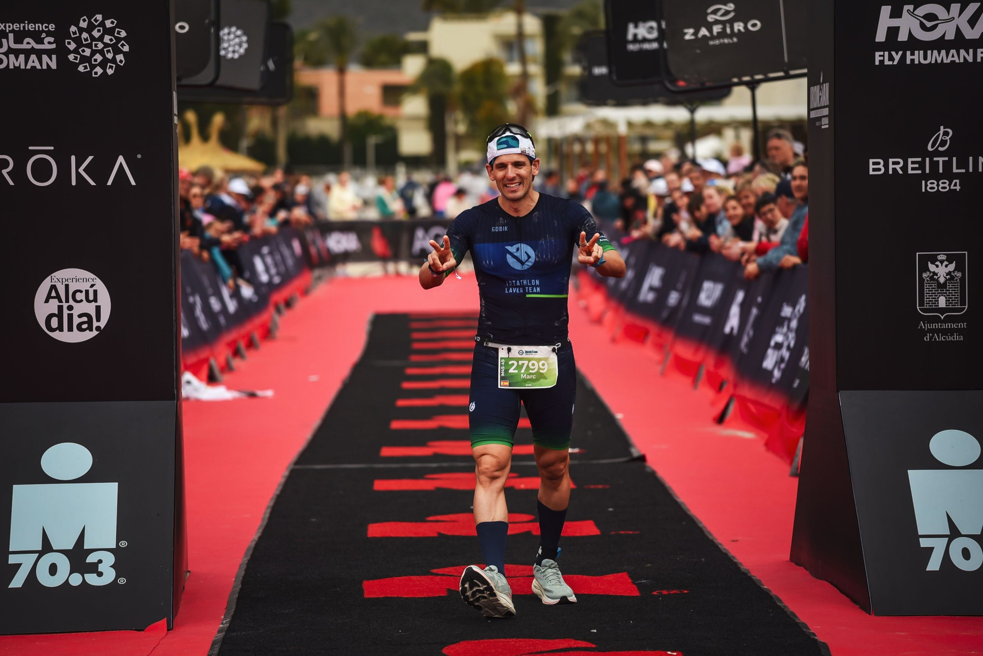 Marc Domínguez cruzando la meta del Ironman 70.3 de Alcudia con el gesto del Spider-Man con ambas manos